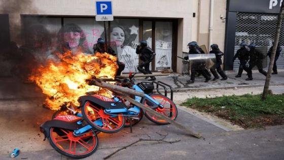 TOPSHOT - French riot police charge past a pile of burning rental bicycles during a demonstration on the 11th day of action after the government pushed a pensions reform through parliament without a vote, using the article 49.3 of the constitution, in Paris on April 6, 2023. - France on April 6, 2023 braced for another day of protests and strikes to denounce French President's pension reform one day after talks between the government and unions ended in deadlock. (Photo by Thomas SAMSON / AFP)