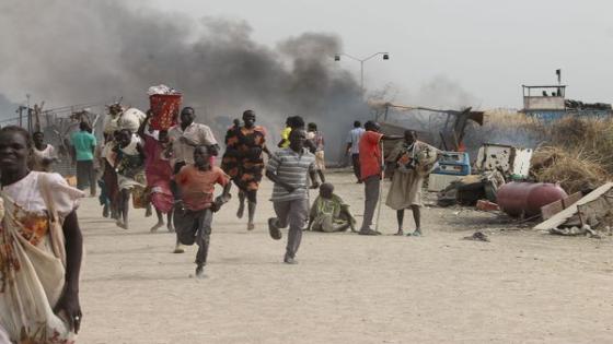 TOPSHOT - South Sudanese civilians flee fighting in an United Nations base in the northeastern town of Malakal on February 18, 2016, where gunmen opened fire on civilians sheltering inside killing at least five people. Gunfire broke out in the base in Malakal in the northeast Upper Nile region on February 17, 2016 night, with clashes continuing on Thursday morning that left large plumes of smoke rising from burning tents in the camp which houses over 47,000 civilians. / AFP / Justin LYNCH (Photo cr